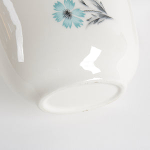 Close-up of a white ceramic creamer cup with floral design