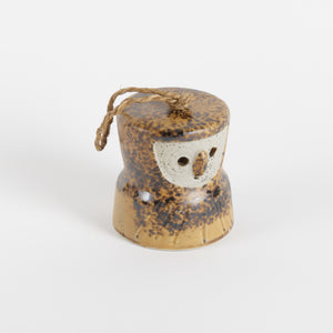 Small ceramic owl bell with a string on a white background