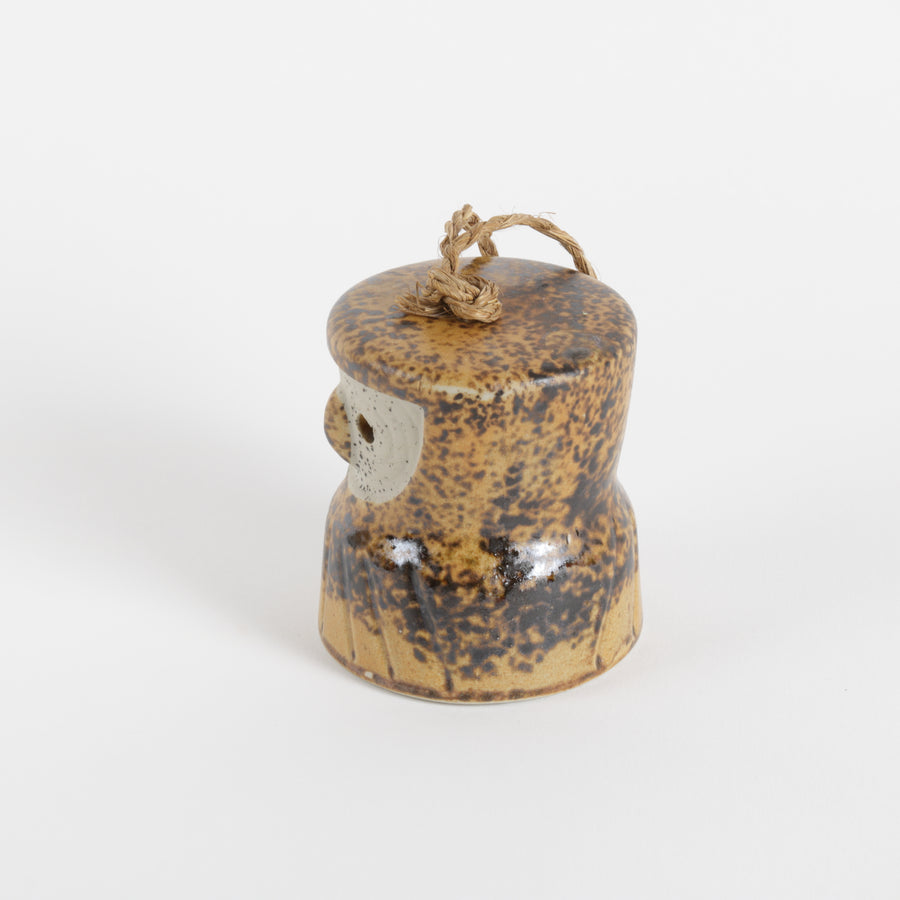 Small ceramic owl bell with a string on a white background