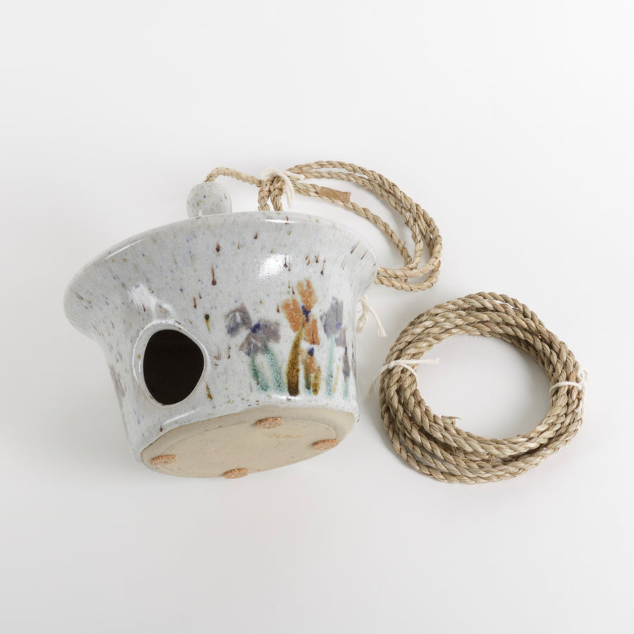 Ceramic birdhouse with speckled texture and rope handle on a white background