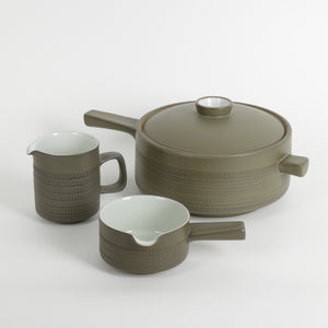 Three-piece ceramic cookware set in a muted olive green color, featuring a lidded pot with a textured exterior, a matching pitcher, and a small saucepan, all on a clean white background.