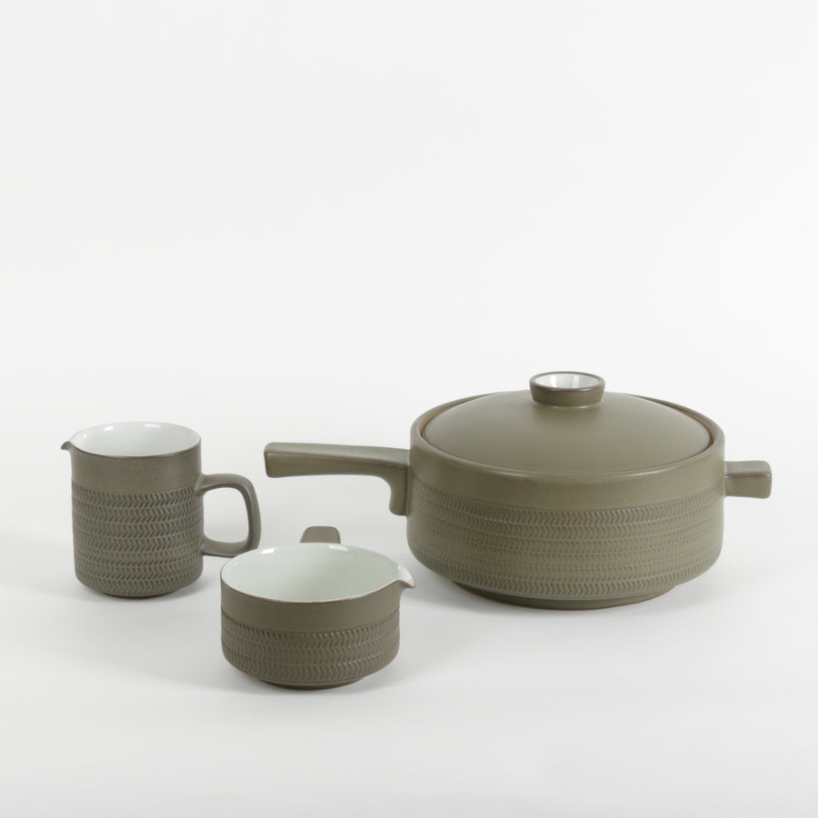 Three-piece ceramic cookware set in a muted olive green color, featuring a lidded pot with a textured exterior, a matching pitcher, and a small saucepan, all on a clean white background.