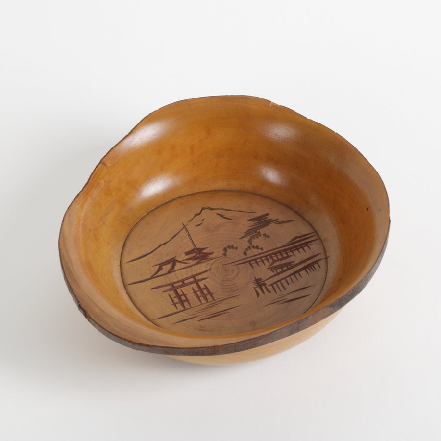 Wooden bowl with engraved design on a white background