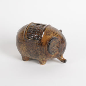 Brown ceramic elephant piggy bank with textured design on a white background