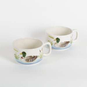 Two ceramic cups with duck illustrations on a white background