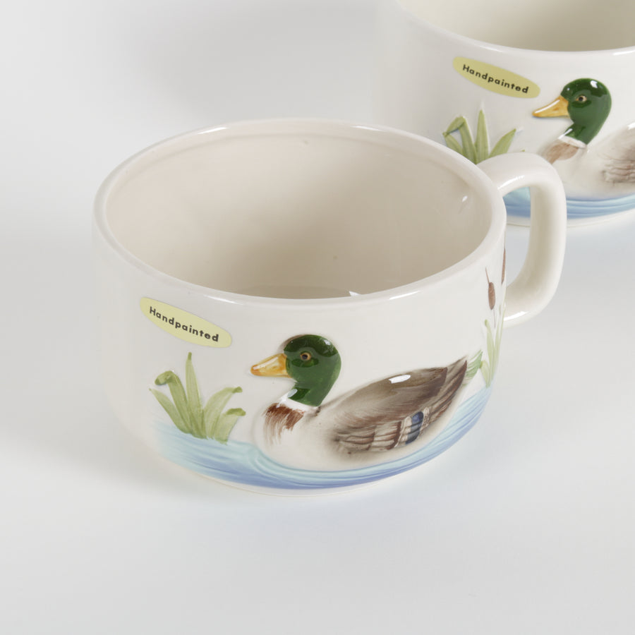 Two ceramic cups with duck illustrations on a white background