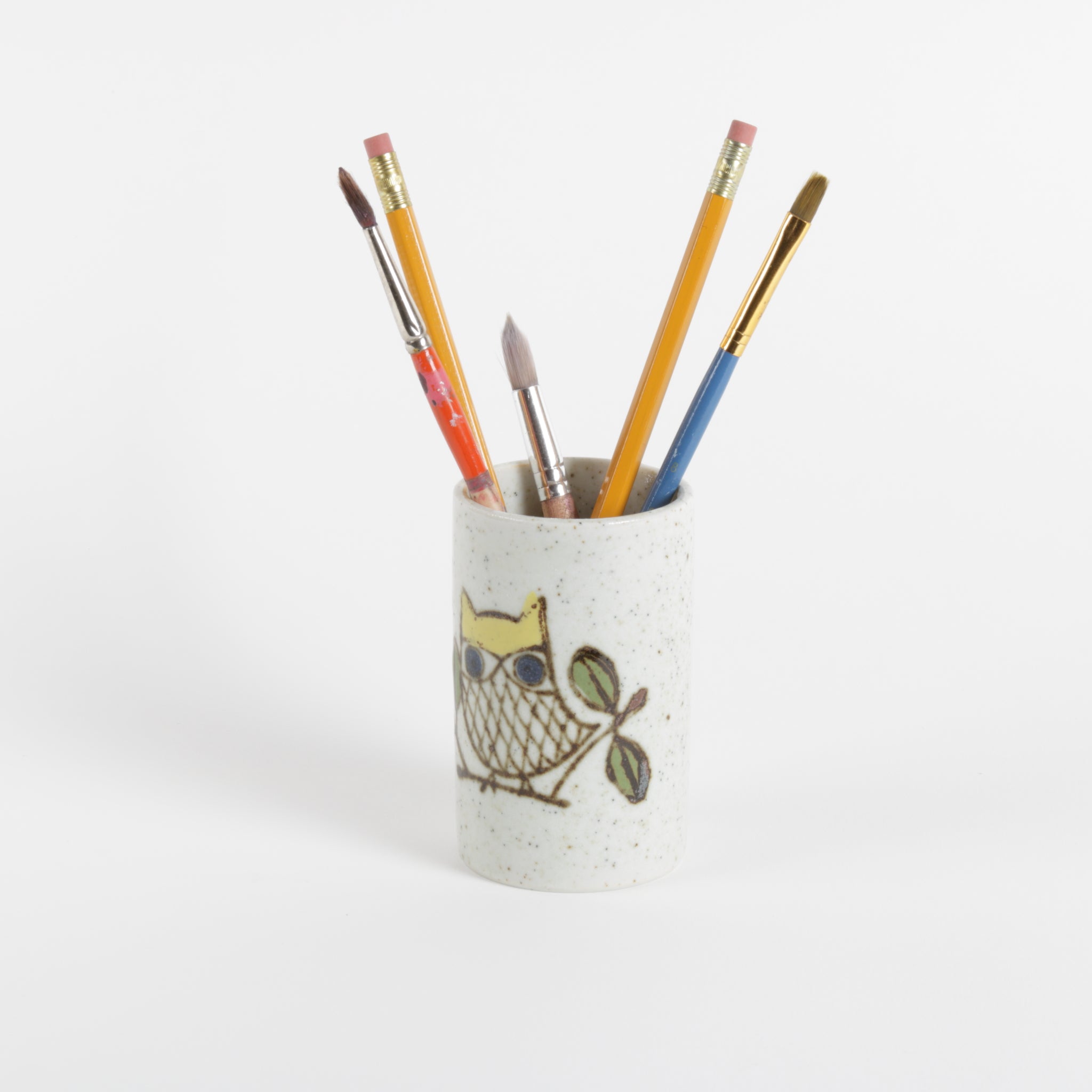 Ceramic pen holder with owl design holding colorful pencils on a white background