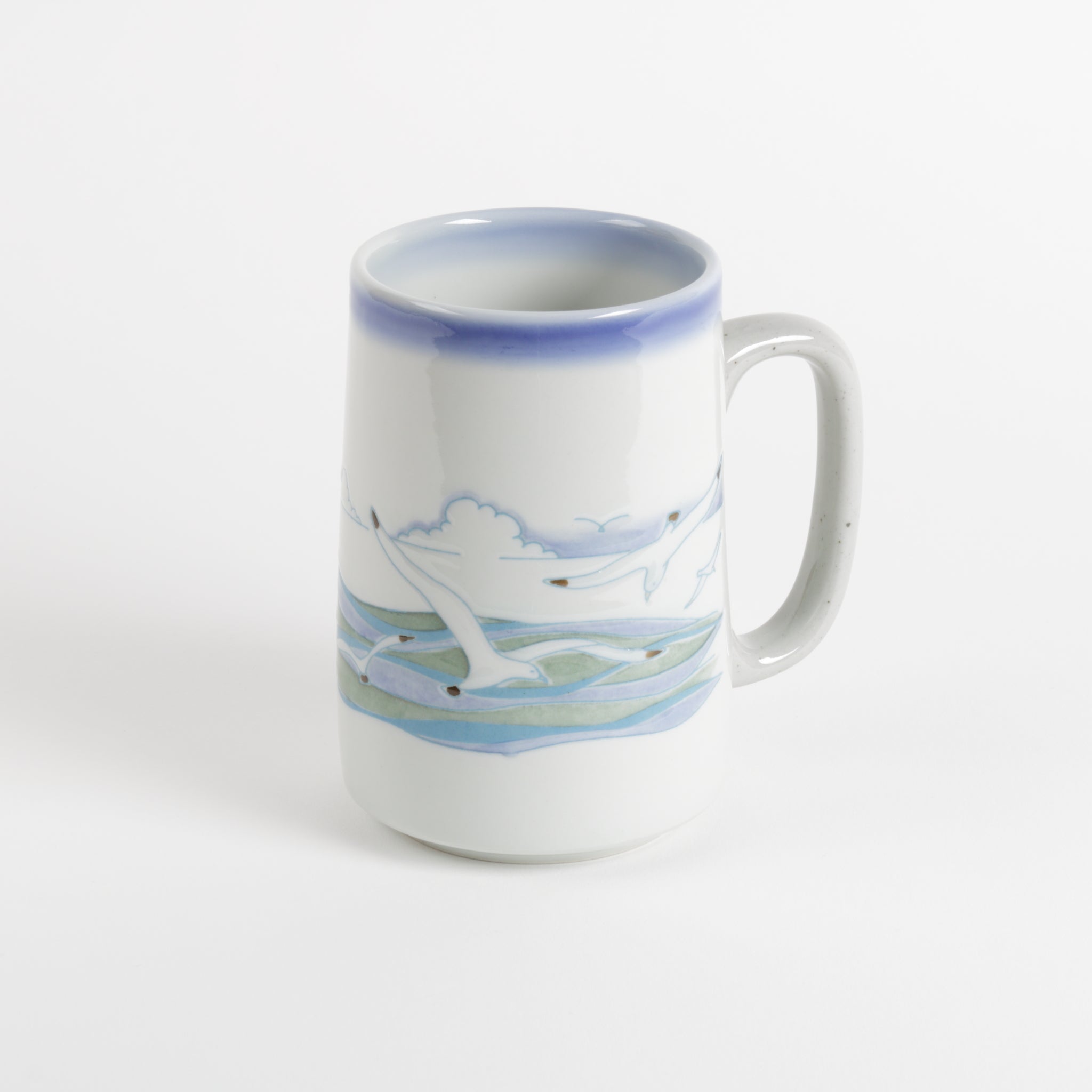 Tall ceramic coffee mug with seagulls in the foreground and horizon