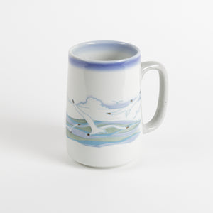 Tall ceramic coffee mug with seagulls in the foreground and horizon