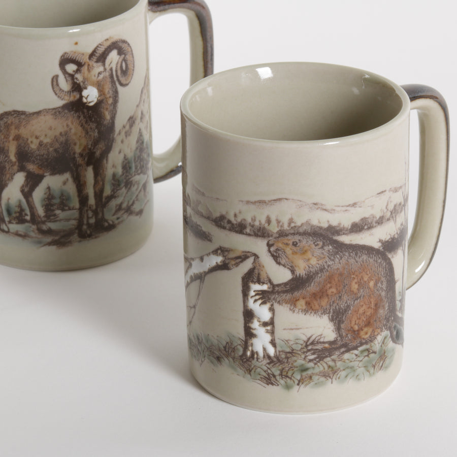 ceramic mugs with artistic scenes of ram sheep and beavers photographed against a white background