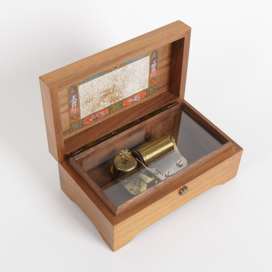 Wooden closed box with a brass round switch on a white background