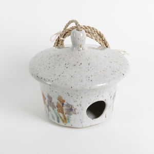 Ceramic birdhouse with speckled texture and rope handle on a white background