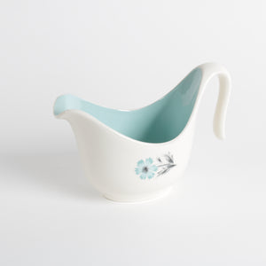 White ceramic creamer cup with integrated spout and handle, aqua interior and floral design