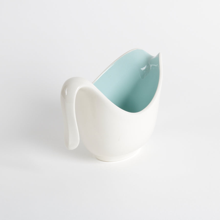 White ceramic creamer cup with integrated spout and handle, aqua interior and floral design