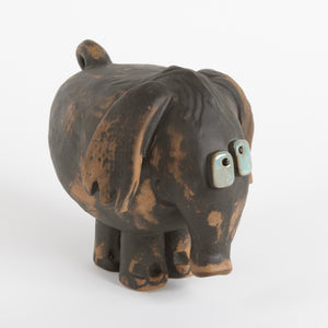 Ceramic elephant sculpture with brown body and blue eyes against white background