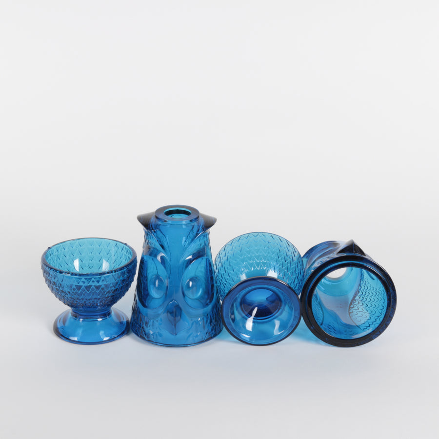 Two blue glass owl lanterns with textured design on a white background