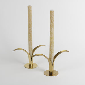 Two solid brass lily shaped candlesticks with long candles