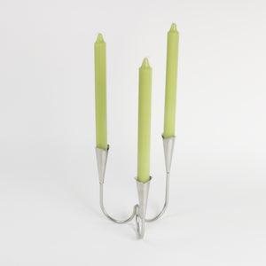 Hans Jensen stainless 3 legged candleholder showing with 3 green tapers