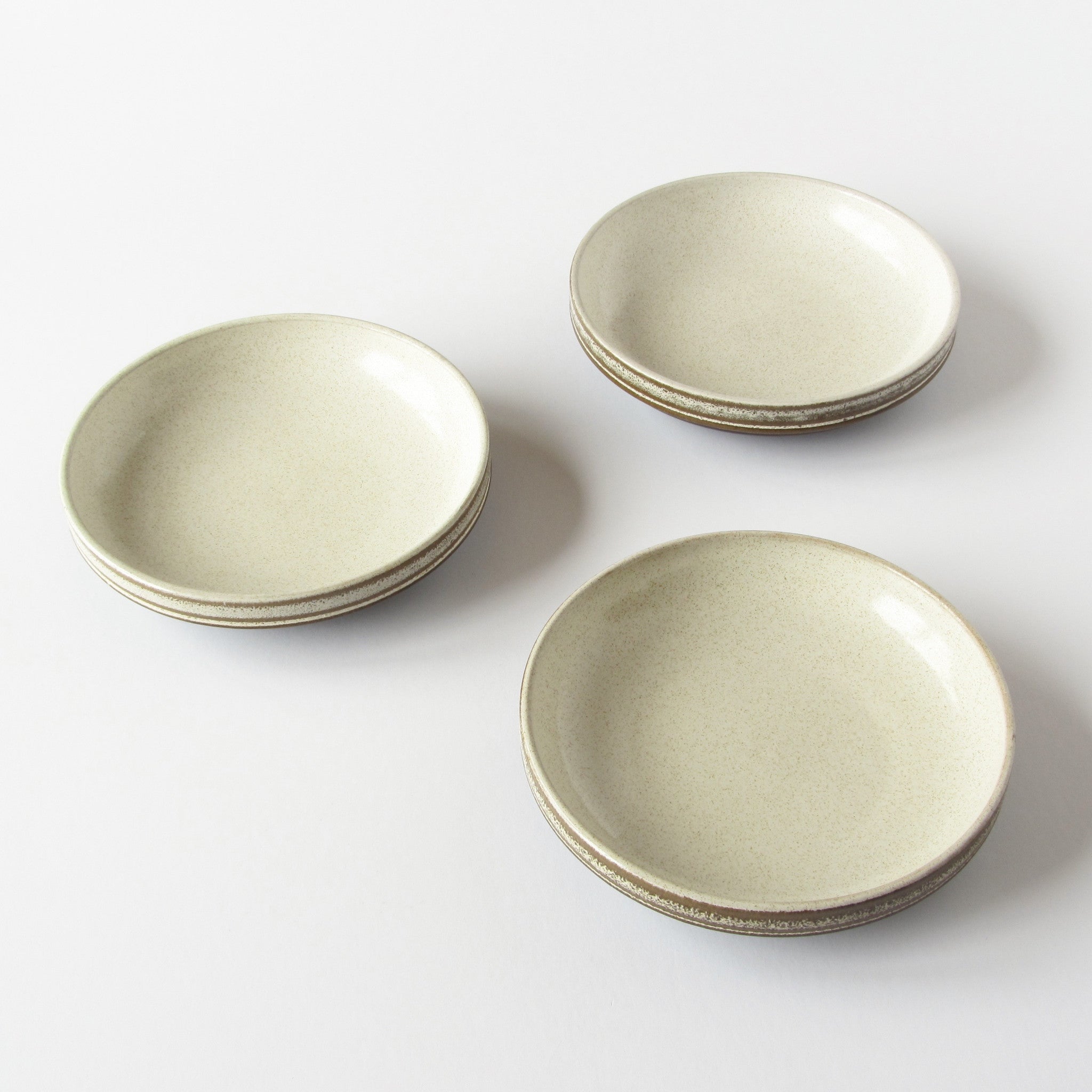 3 stoneware bowls cream in color with brown rims against a white background