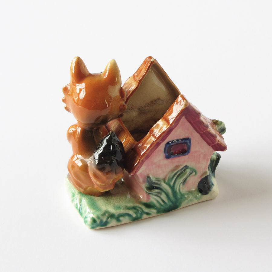 Antique ceramic fox planter to the side of house, checked glaze